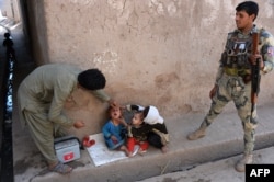 FILE - An Afghan health worker administers polio drops to a child in the Surkh Rod district of Nangarhar province, Aug. 29, 2016. According to Afghan president Ashraf Ghani, 39 percent of the Afghan population lives on less than $1.35 a day.
