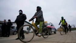 Vietnamese workers who are helping construct the first Chinese car tire factory in Europe ride bicycles past security officers near the northern Serbian town of Zrenjanin, 50 kilometers north of Belgrade, Nov. 18, 2021.