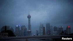 FILE - People walk with umbrellas on a bridge amid rains and winds brought by Typhoon Muifa, in Shanghai, Sept. 14, 2022. 