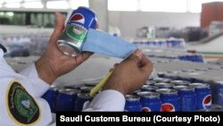 Saudi Customs' officer cuts open Pepsi labels from cans and finds they are actually beer.