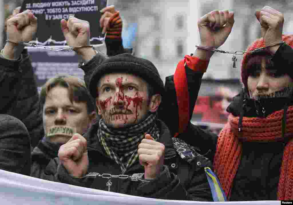 Para pendukung integrasi Pro-Eropa dengan mulut yang ditutup berunjuk rasa menentang undang-undang baru yang disetujui di Kiev, Ukraina. Pendukung Presiden Ukraina Yanukovich mengesahkan sebuah undang-undang pada hari Kamis dalam upaya untuk mengekang protes-protes anti-pemerintah.