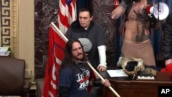 FILE - In this image from U.S. Capitol Police video, Paul Allard Hodgkins of Tampa, Florida, front, stands in the well on the floor of the U.S. Senate at the Capitol in Washington, Jan. 6, 2021. 