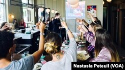 Les Français lèvent leurs verres après la victoire d'Emmanuel Macron à La Jambe, à Washington DC, le 7 mai 2017. (VOA/Nastasia Peteuil)