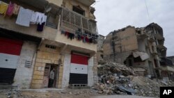 FILE - Adnan Sabbagh stands in the door of his house that was damaged by shelling in Aleppo, Syria, Jan. 21, 2018. 