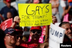 A person holds up a "Gays for Trump" sign as then-Republican presidential nominee Donald Trump holds a campaign event in Orlando, Fla., Nov. 2, 2016.