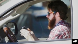 FILE - An man works his phone as he drives through traffic in Dallas, Tuesday, Feb. 26, 2013. Texas lawmakers are considering a statewide ban on texting while driving. (AP Photo/LM Otero)