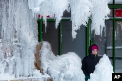 A woman passes an ice-covered fountain in New York's Bryant Park, Jan. 5, 2018. Frigid temperatures, some that could feel as cold as minus 30 degrees, moved across the East Coast on Friday as the region attempted to clean up from a massive winter storm.