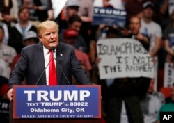 FILE - Republican presidential candidate Donald Trump speaks at a rally as a man holds up a sign that reads "Islamophobia is not the answer" in Oklahoma City, Feb. 26, 2016.