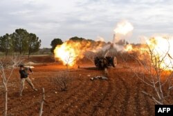 An opposition fighter fires a gun from a village near al-Tamanah during ongoing battles with government forces in Syria's Idlib province on Jan. 11, 2018.