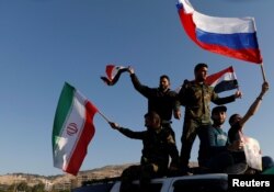 Sirijci mašu iranskim, ruskim i sirijskim zastavama tokom protesta protiv vazdušnih napada koje predvoje SAD, u Damasku, Sirija, 18. aprila 2018.