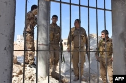 FILE - Fighters from the Kurdish People's Protection Units (YPG) monitor troop movements in the area of Afrin, along Syria's northern border with Turkey, June 9, 2017.