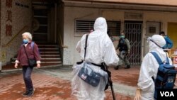 On Feb. 11, 2020, an AP crew in full protective gear is filming in front of the Tsing Yi public housing building in Hong Kong. Two units in the building had confirmed coronavirus cases and other residents were evacuated. (Photo taken by VOA Cantonese stringer Iris Tang)