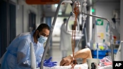 A medical staff member speaks with a COVID-19 patient in the infectious disease ward of the Strasbourg University Hospital, eastern France, Jan. 13, 2022.