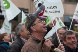 FILE - A farmer wearing a wolf hat shouts slogans during a protest in Madrid, Spain, Dec. 14, 2016. The protest was to highlight problems affecting farmers and ranchers including wolf attacks, EU funding and problems of milk producers in the region.