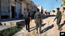 Members of the Kurdish internal security forces pass damaged shops in the area where an explosion hit U.S.-led coalition vehicles, killing an American soldier and a British soldier, in Manbij, Syria, March 31, 2018.