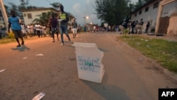 Les habitants passent devant un bulletin de vote dans une rue après que des personnes non identifiées aient endommagé un bureau de vote à Grand Bassam, le 16 décembre 2018, lors d'élections municipales et régionales partielles.