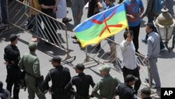 Un homme brandit le drapeau d'Amazigh devant des policiers lors d'une manifestation à Rabat, Maroc, 11 juin 2017.