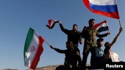 Syrians wave Iranian, Russian and Syrian flags during a protest against U.S.-led air strikes in Damascus, Syria April 14,2018.