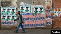 A man walks past campaign posters outside a polling center in the capital Antananarivo, Oct. 25, 2013.