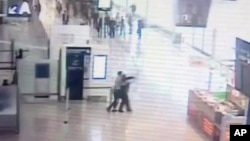 In this image taken from video of CCTV footage provided to AP on the condition that its source not be revealed, suspected Islamic extremist Ziyed Ben Belgacem, center left, holds a soldier after grabbing her from behind at Paris’ Orly airport, March 18, 2