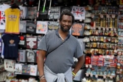 Paul Tomo poses for a photo in front of a souvenir stand in Westminster in London, Wednesday, July 22, 2020. "Two things, if we really needed them why weren't they introduced in the beginning," he said.
