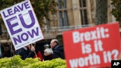 Pro and anti Brexit protesters hold signs as they vie for media attention near Parliament in London, Nov. 16, 2018. Britain's Prime Minister May still faces a threat of a no-confidence vote, after several Conservative Party lawmakers said they had written letters asking for one.