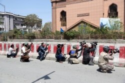 FILE- Afghan journalists work behind a barrier at the site of an attack on the Telecommunication Ministry in Kabul, April 20, 2019. Limiting access to information by the Afghan government is not acceptable, said an official from an Afghan watchdog.