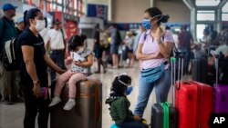 Turis mengenakan masker penutup wajah di Bandara Internasional Havana, Kuba, 23 Maret 2020. 