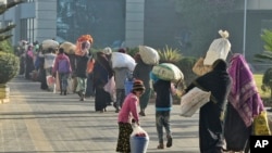Pengungsi Rohingya berjalan dengan barang-barang miliknya untuk dipindahkan ke Pulau Bhasan Char, di Chattogram, Bangladesh, Jumat, 29 Januari 2021. (Foto: AP)