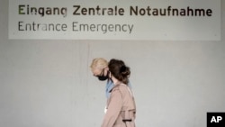 Alexei Navalny's wife Yulia, background, arrives at the Charite hospital in Berlin, Germany, Monday, Aug. 24, 2020. Russian oppositional Alexej Nawalny is being treated at the hospital by German doctors after a suspected poisoning. (Kay Nietfeld/dpa via AP)