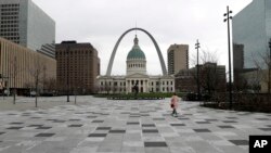 A pedestrian crosses a nearly empty Kiener Plaza Park, March 17, 2020, in St. Louis.