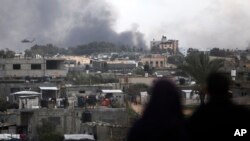 ชาวปาเลสไตน์ดูเฮลิคอปเตอร์บินเหนือคานยูนิส ในฉนวนกาซ่า เมื่อ 15 ก.พ. 2024 (เอพี)