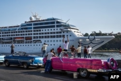 FILE - Cubans watch as the first US-to-Cuba cruise ship to arrive in the island nation in decades glides into the port of Havana, on May 2, 2016.