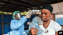 ARCHIVES - Une femme se fait prendre la température dans le cadre de la prévention d'Ebola, à l'entrée de l'hôpital public Macauley à Freetown, Sierra Leone, le 21 janvier 2016.