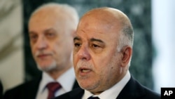 FILE - Iraqi Prime Minister Haider al-Abadi, right, holds a new conference before leaving to the United States at Baghdad airport, April 13, 2015. 