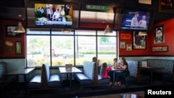 Laura Haque eats lunch with her family between tables closed for social distancing at Bad Daddy's Burger Bar, Smyrna, Georgia, on the day restaurants and theaters were allowed to reopen to the public as part of the phased reopening.