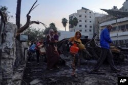 Warga Palestina membawa barang-barang mereka saat meninggalkan rumah sakit al-Ahli, yang mereka gunakan sebagai tempat berlindung, di Kota Gaza, Rabu, 18 Oktober 2023. (Foto: AP)