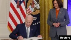 U.S. President Joe Biden signs an Executive Order about Artificial Intelligence as Vice President Kamala Harris looks on, in the East Room at the White House in Washington, U.S., October 30, 2023. (REUTERS/Leah Millis)