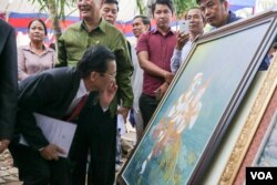 មន្រ្តីក្រសួងវប្បធម៌មួយរូបមើលរូបគំនូររឿងរាមកេរ្ត៍ដែលទទួលបានពានរង្វាន់នៅក្នុងពិធីតាំងពិពណ៌ស្នាដៃសិល្បៈខ្មែរ និងការចែកពានរង្វាន់គំនូររឿងរាមកេរ្តិ៍ នៅថ្ងៃព្រហស្បតិ៍ ទី៣ ខែវិច្ឆិកា ឆ្នាំ២០១៦ រាជធានីភ្នំពេញ។