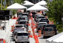 FILE - Lines of cars wait at a drive-through coronavirus testing site outside the Miami Beach Convention Center, in Miami Beach, Florida, June 26, 2020.