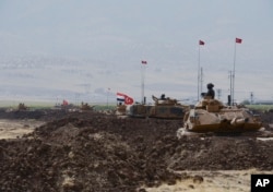 Turkish and Iraqi soldiers sit on Turkish tanks during the exercises in Silopi, near the Habur border gate with Iraq, southeastern Turkey, Sept. 26, 2017.