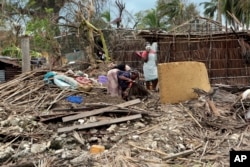 A family picks up a few items from their house, which was damaged by Cyclone Kenneth when it struck Ibo island north of Pemba city in Mozambique, May, 1, 2019. The government has said more than 40 people have died after the cyclone made landfall on Thursday.