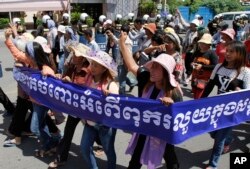 Cambodian activists shout slogans during a march toward the National Assembly, in Phnom Penh, Cambodia, Thursday, May 29, 2014.