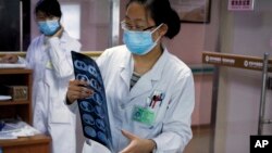 In this Thursday, Dec. 8, 2016 photo, a nurse looks at a CT scan of a lung cancer patient before passes to a doctor at the Jingdong Zhongmei private hospital in Yanjiao, China's Hebei Province. 