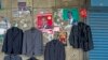 Election posters share wall space with a street trader's jackets, ahead of a presidential election, in Lusaka, Jan. 14, 2015.