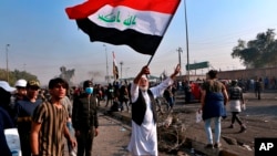 A protester waves the national flag during clashes with security forces in central Baghdad, Iraq, Jan. 20, 2020.