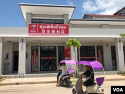 ជនជាតិ​ចិន​ពីរនាក់ ជិះម៉ូតូ ដោយ​មាន​ប្លាស្ទិច​បាំង​កម្តៅ​ថ្ងៃ នៅ​ខាងមុខ​ផ្សារ​ចិន នៅក្នុង​ខេត្តកោះកុង នៅថ្ងៃទី ៣ ខែមេសា ឆ្នាំ២០១៩។ (ស៊ុន ណារិន/VOA)