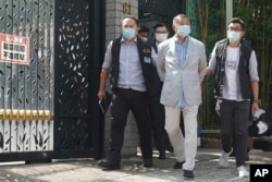 FILE - Hong Kong media tycoon Jimmy Lai, center, who founded local newspaper Apple Daily, is arrested by police officers at his home in Hong Kong, Monday, Aug. 10, 2020.
