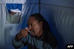 45-year-old Oscar Tyumre uses an HIV self-testing kit, administered by students from the University of the Witwatersrand in Hillbrow, Johannesburg, on March 19, 2018.