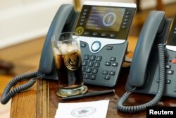 FILE - President Donald Trump's glass of Diet Coke with the presidential seal on it sits on his desk in front of his phones in the Oval Office at the White House, in Washington, Dec. 11, 2018.